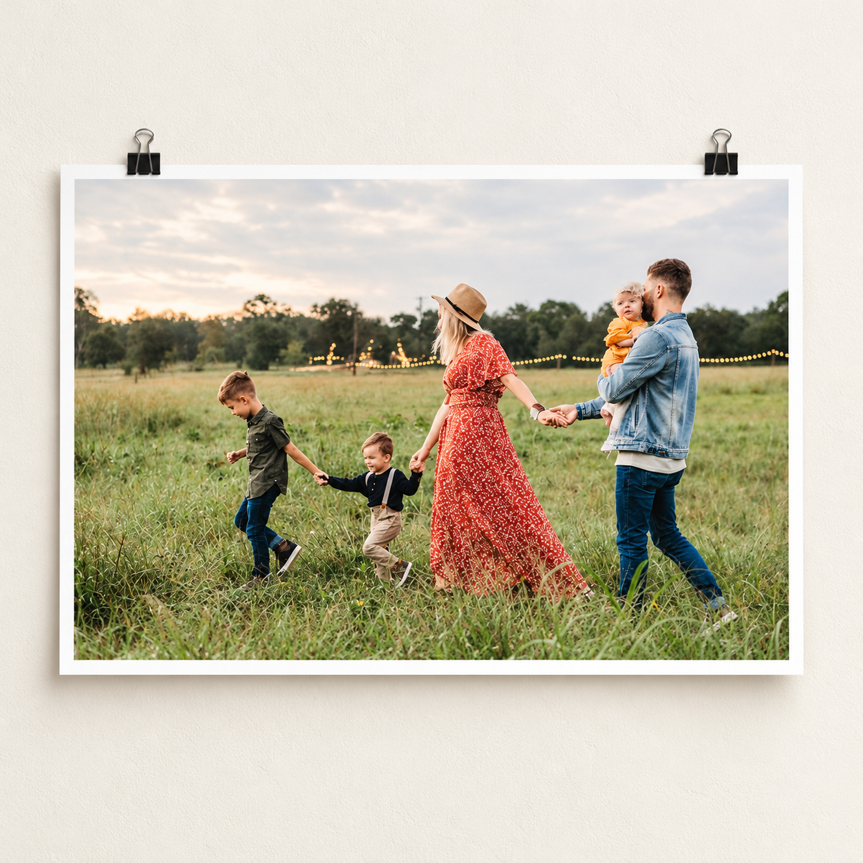 Unframed landscape photo poster showing a family walking through a meadow, with a white border and black clips